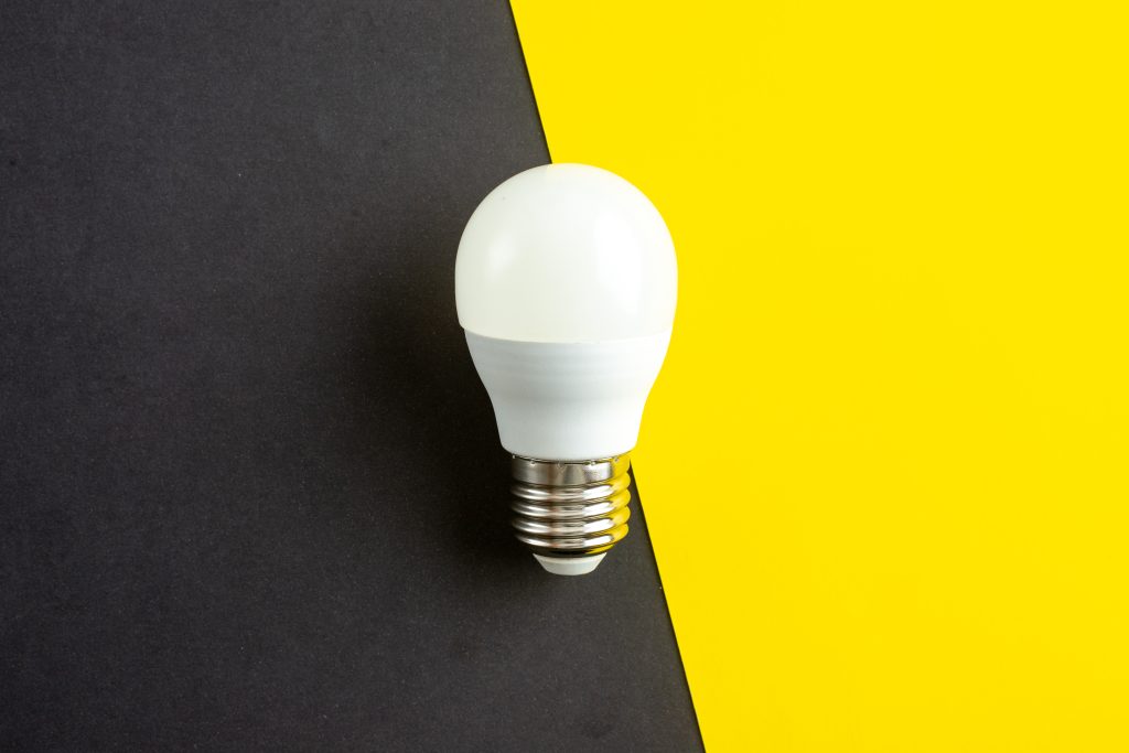 LED lightbulb on black and yellow lumen background for energy efficiency